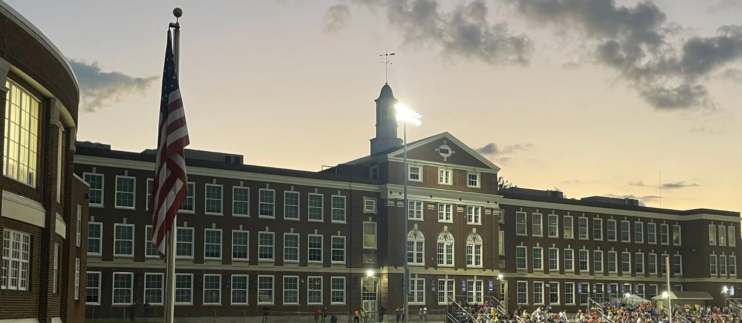morgantown high school red brick building at night with clouds and lights 
