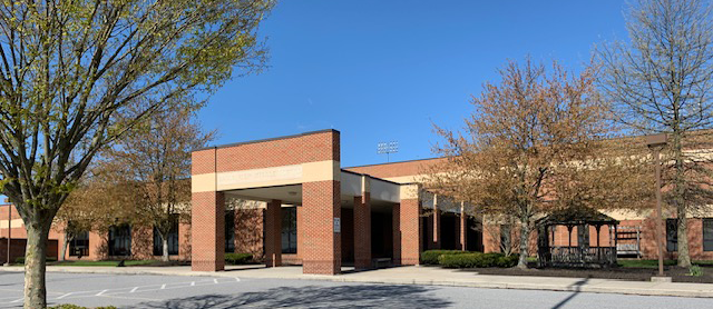 Picture of brick school building with blue sky and trees.