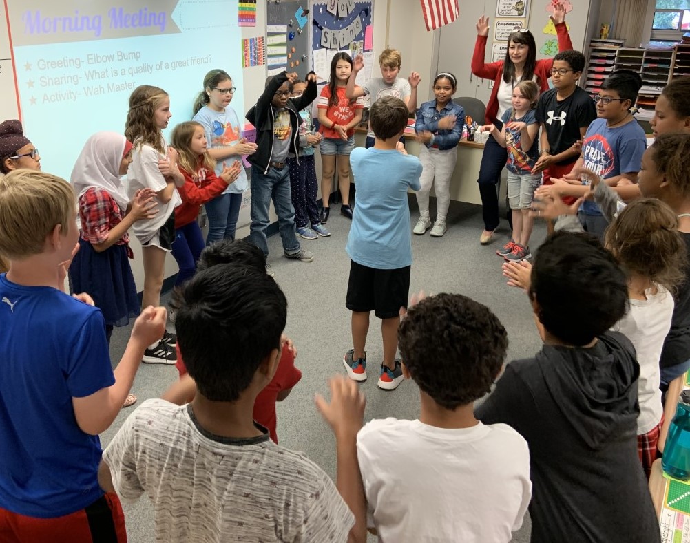 Children gathered in a classroom, participating in an interactive lesson with their teacher.