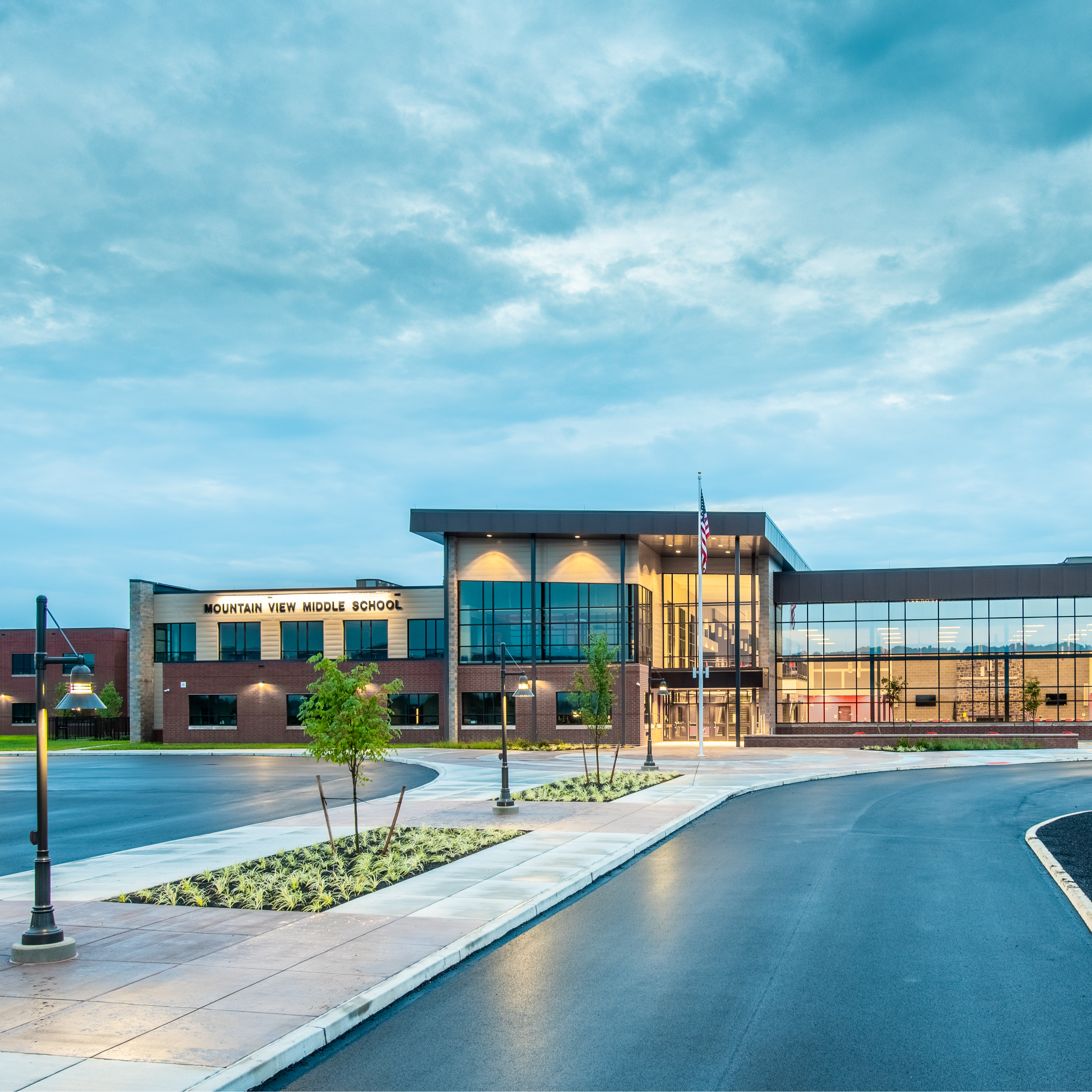 Photo of school with glass and brick front and cloudy blue skyline