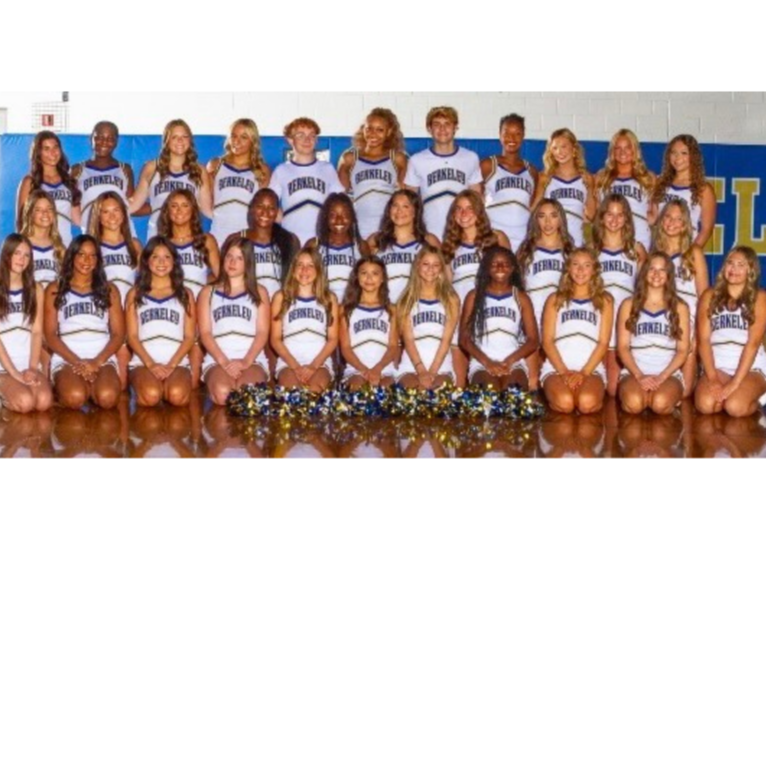 Cheerleaders pose for a photo in matching white and blue uniforms, arranged in rows, with pom-poms on the floor.