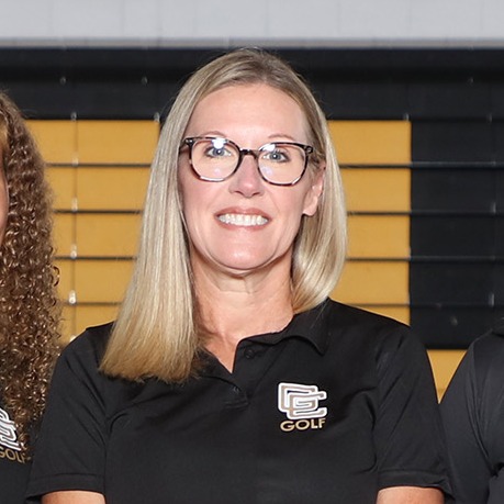 A group of women in black uniforms and sneakers on a basketball court with "Goose Creek High School" sign.