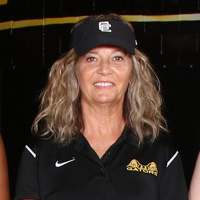A team of young women poses for a photo on a basketball court with a "Gators" sign.
