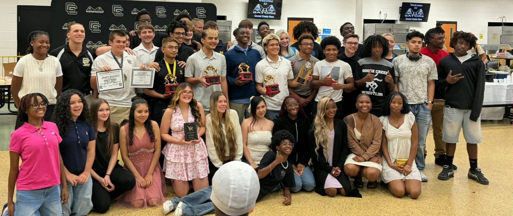 A group of young people in casual attire holding awards and posing for a photo.