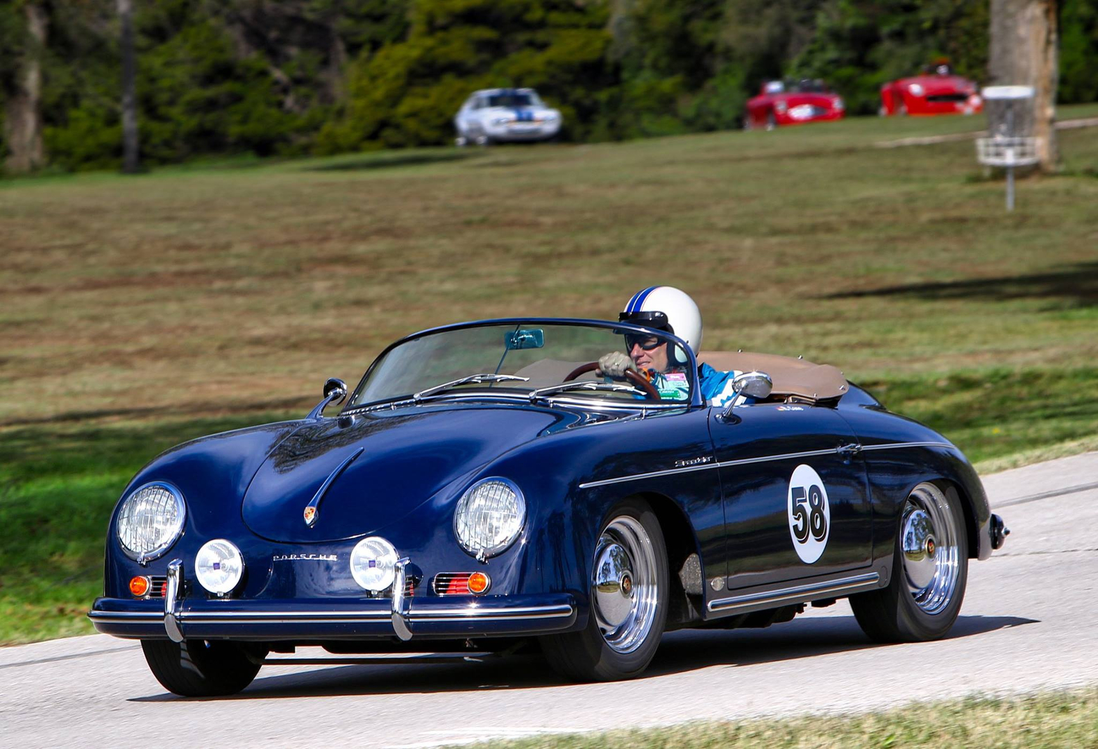 a man driving a blue convertible sports car down a road