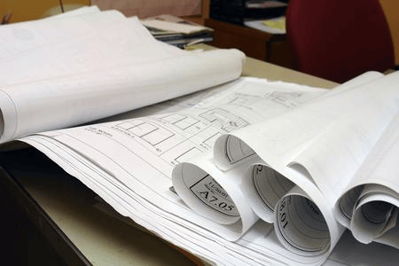 A collection of architectural plans and blueprints rolled and spread out on a table