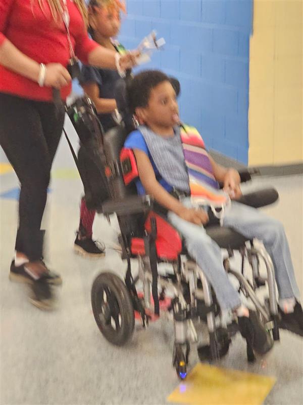 teacher following the child on the wheelchair 
