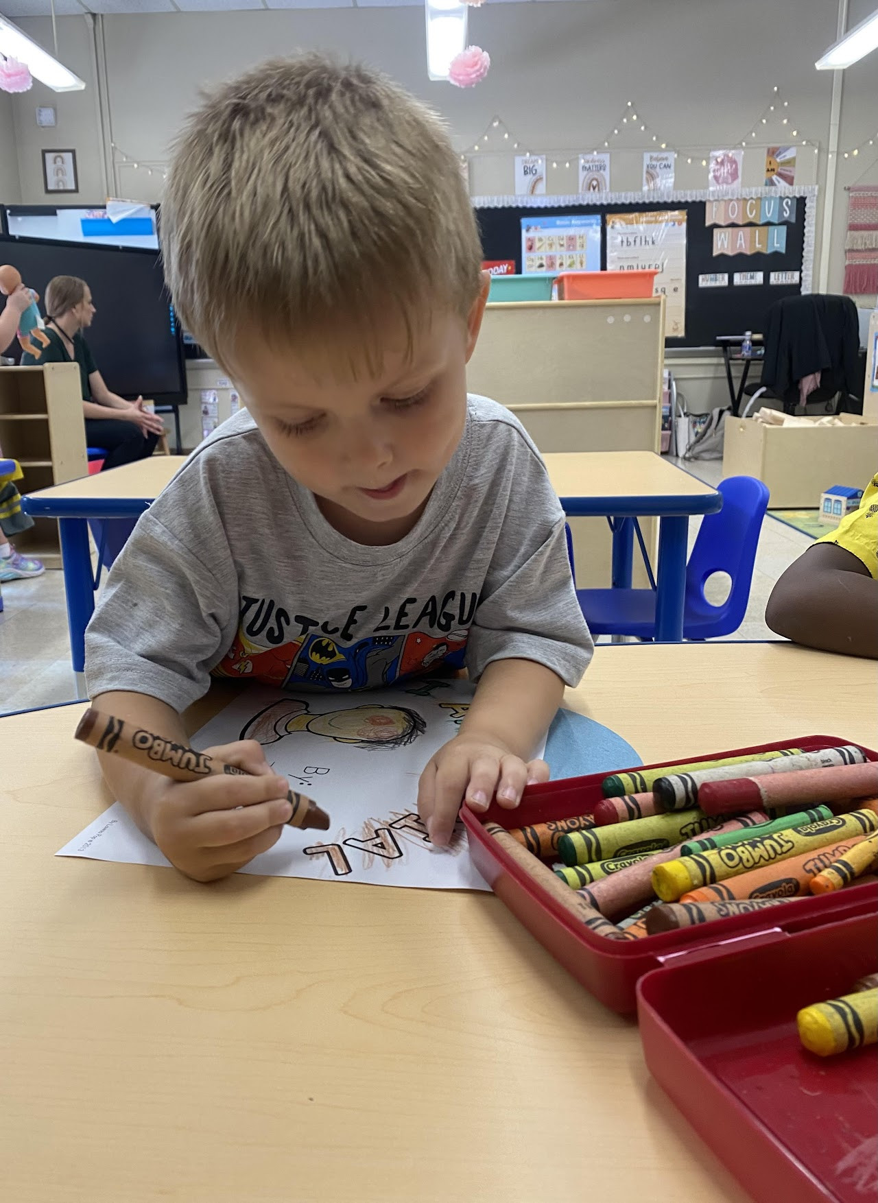 child coloring a paper with crayonbs