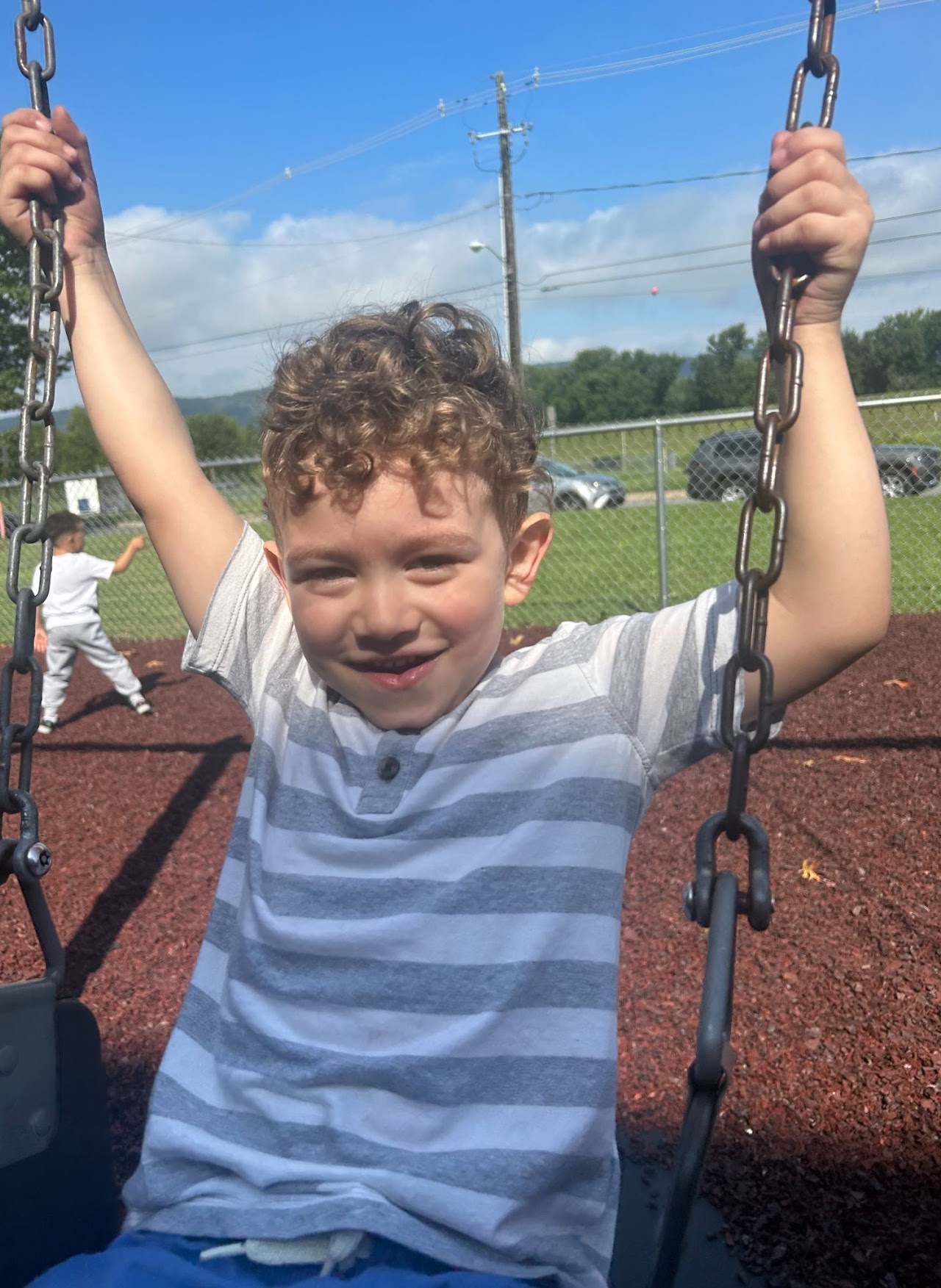 A young boy enjoying himself on the swing set