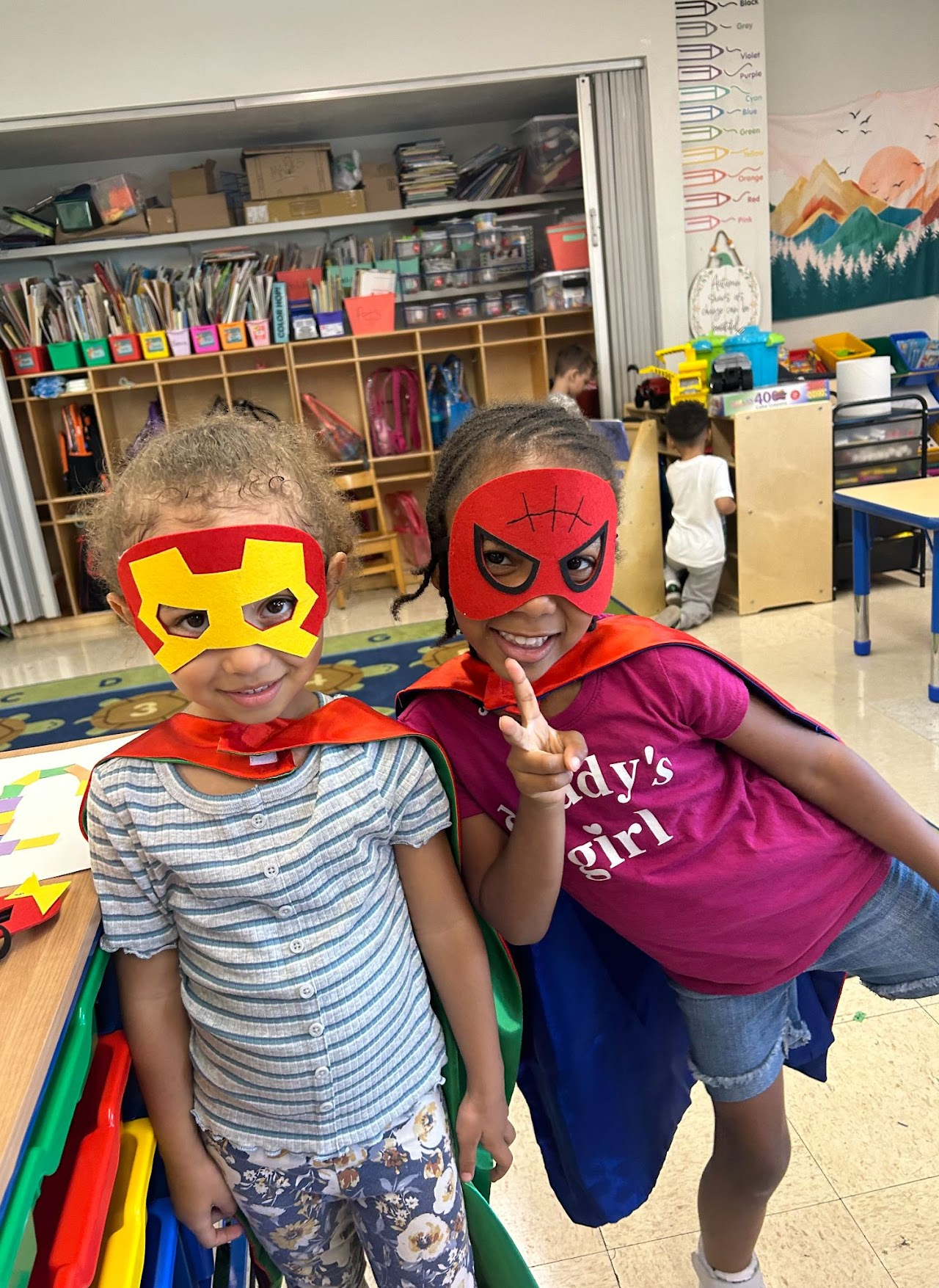 Two children wearing masks and capes for customer party