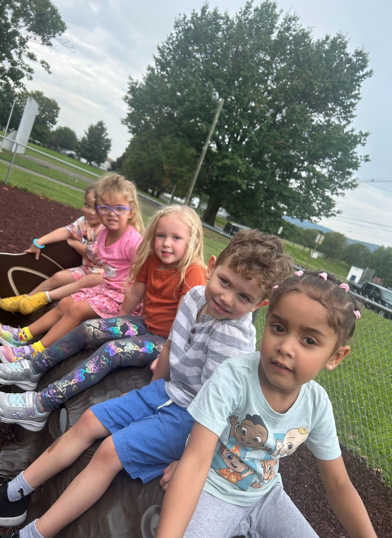 Four children sitting by the park bench