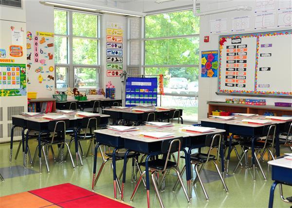 Student desks linked up inside a classroom with large windows.