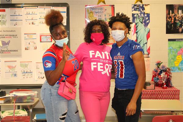 3 students wearing a face mask smiling
