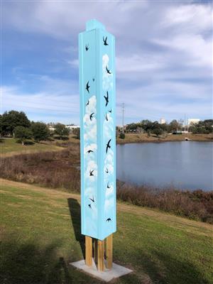 Blue pole with birds in front of lake.