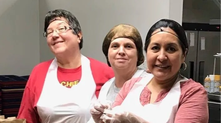 cafeteria cooks cooking but smiling at the camera