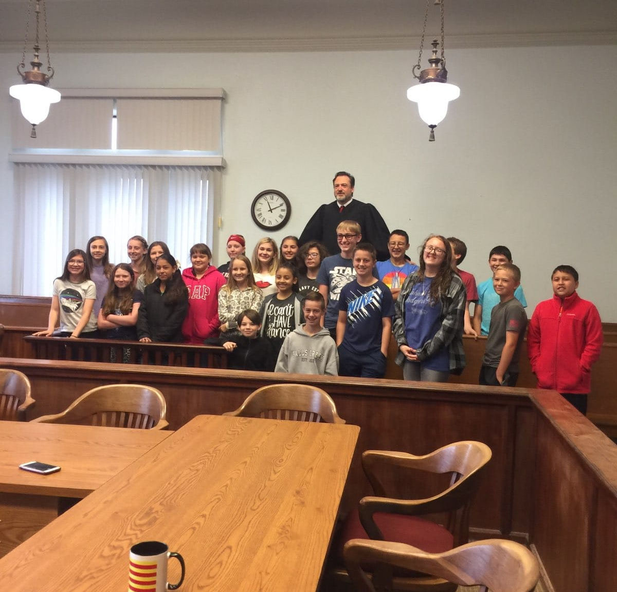 kids and their teacher at a classroom in the back, looking at the camera