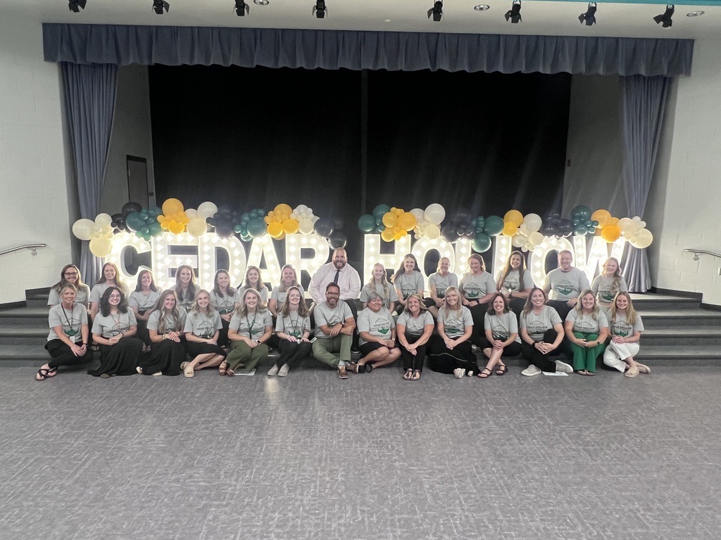 All staff at Cedar Hollow elementary sitting in front of the stage with huge light up letters spelling out Cedar Hollow with balloons.