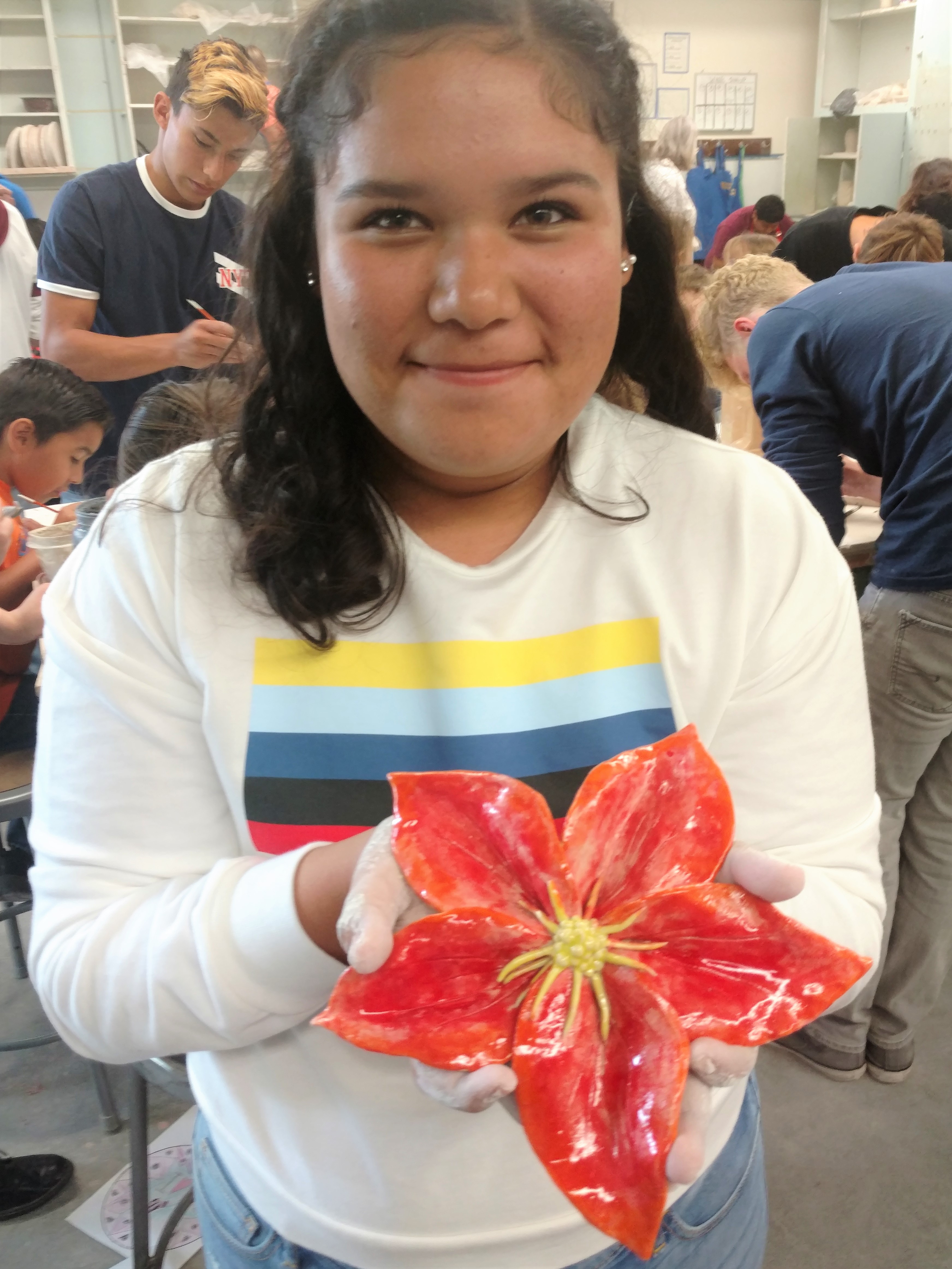 A girl holding up a ceramic flower