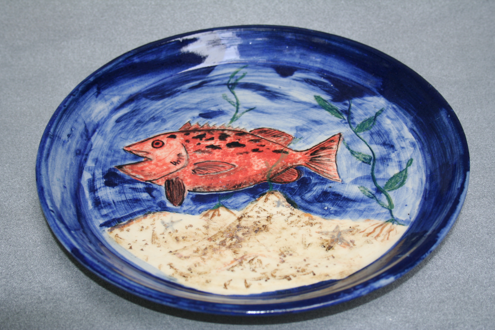 A ceramic plate along with a freshly painted fish over the base