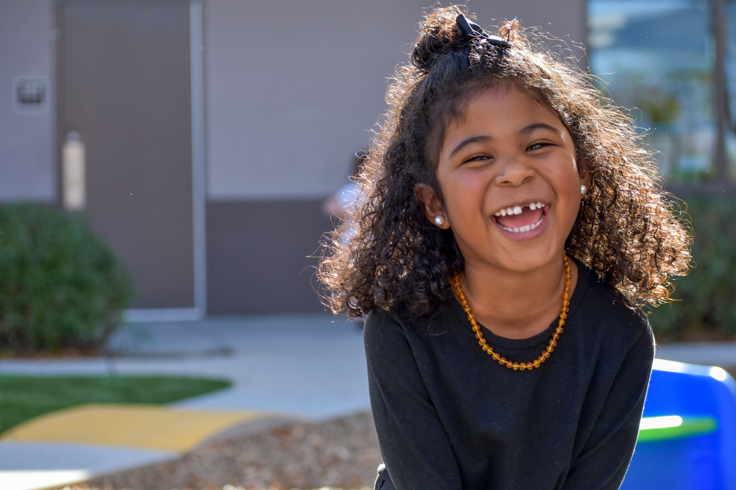  A smiling girl in a black shirt looks at the camera.