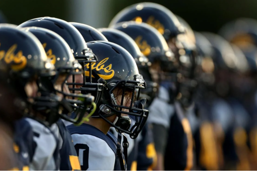  A line of football players in helmets with the team name "Cabs" visible, ready for a game.