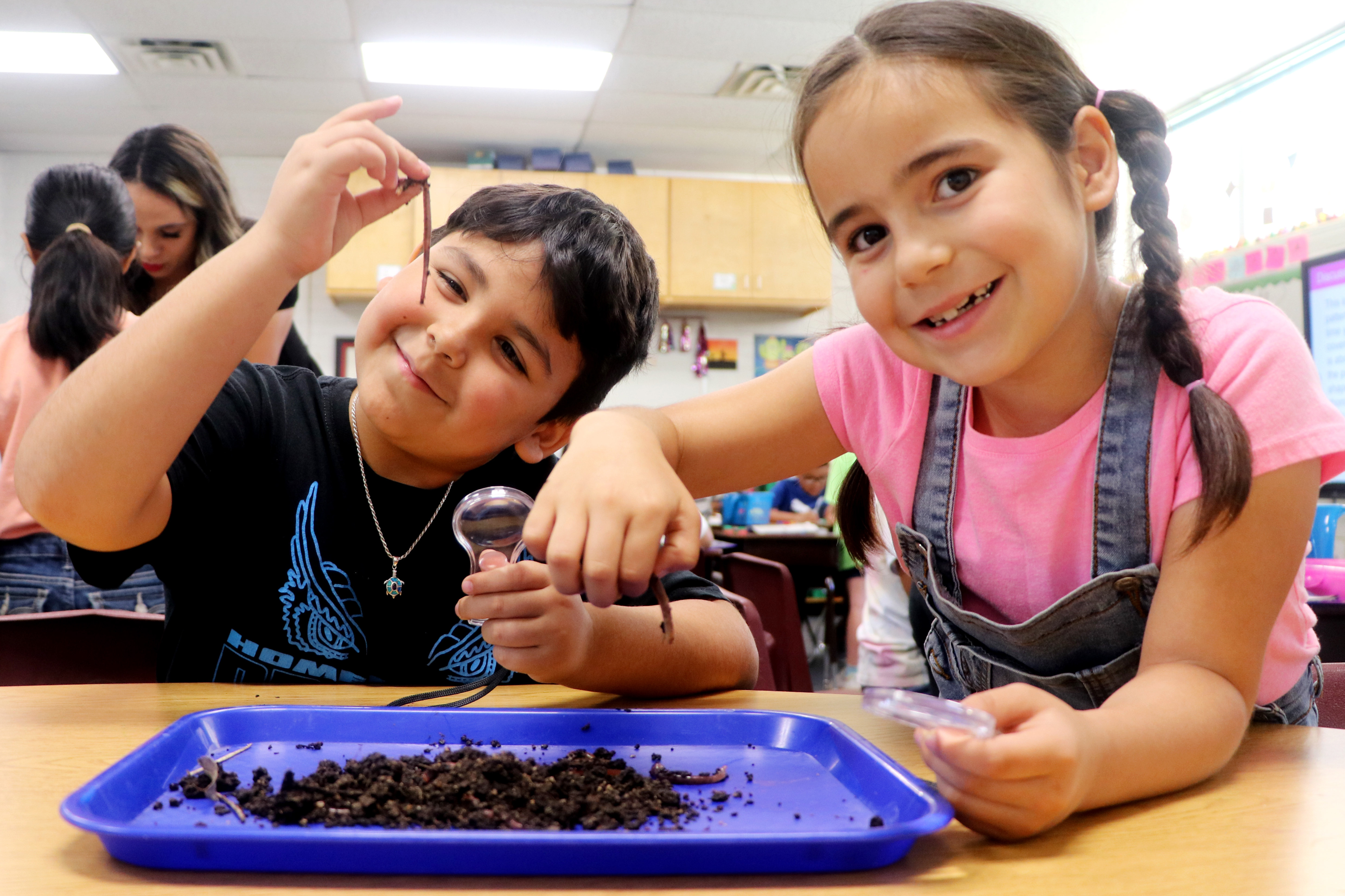 two young kids observing worms