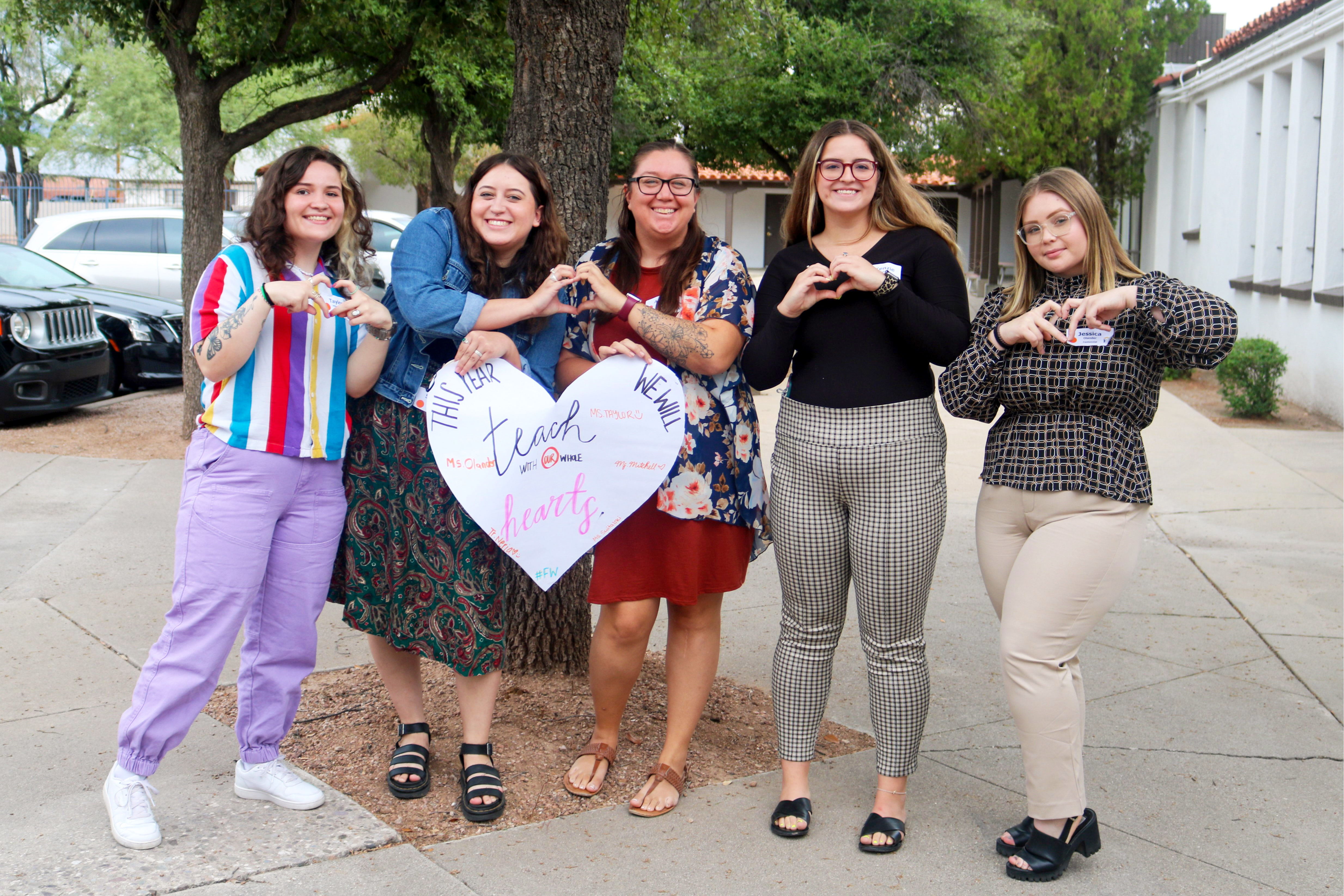 Flowing Wells teachers celebrating mentorship and support with a heart-shaped sign.