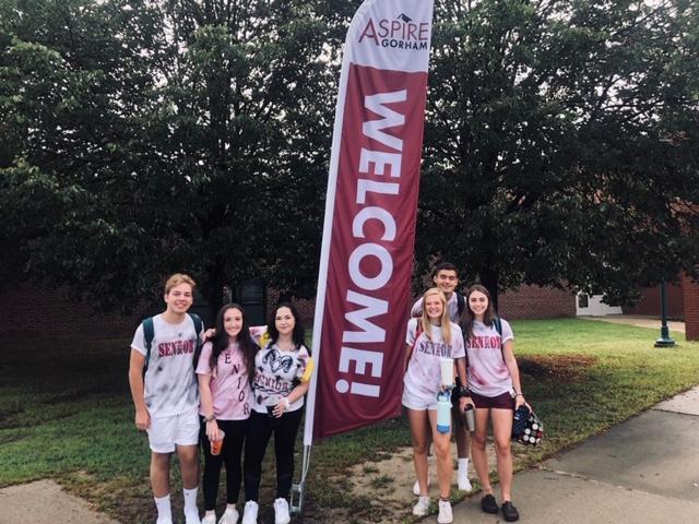 A group of young people standing next to a welcome sign