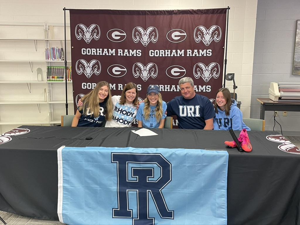 Girls sitting at a table with a "Gorham Rams" sign, showing support for their school team.