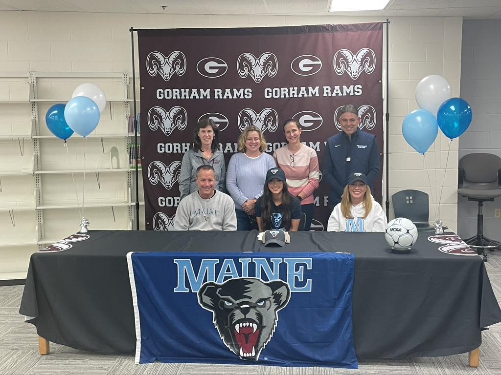 Maine girls basketball team smiles for photo at signing table.