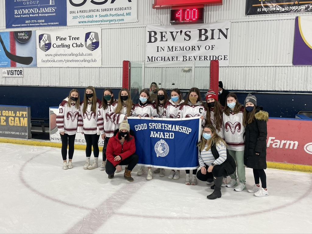 Smiling girls hockey team holds up banner for team photo.