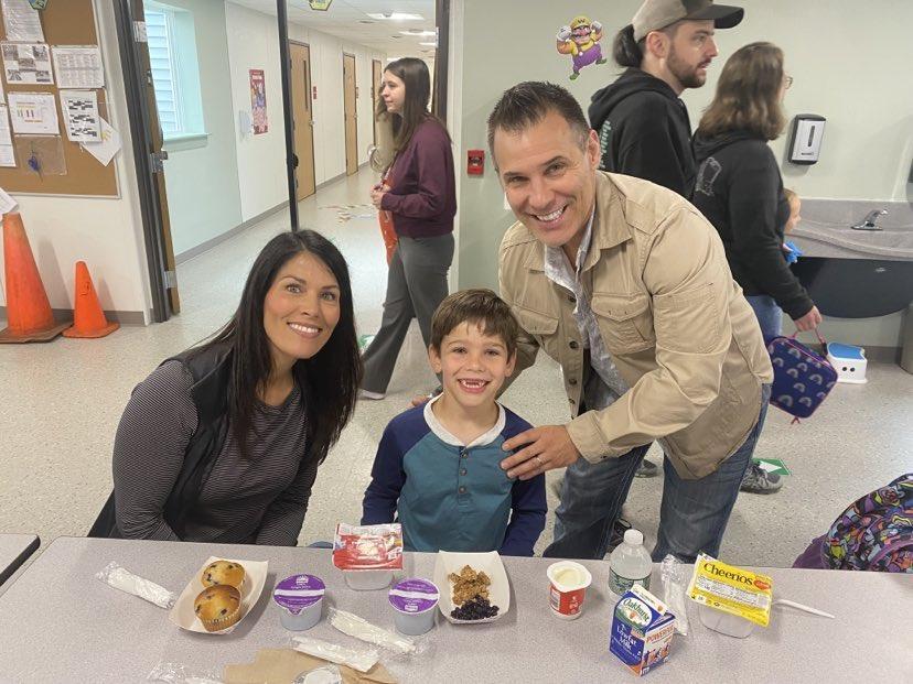 A man and a woman standing next to a boy at a table