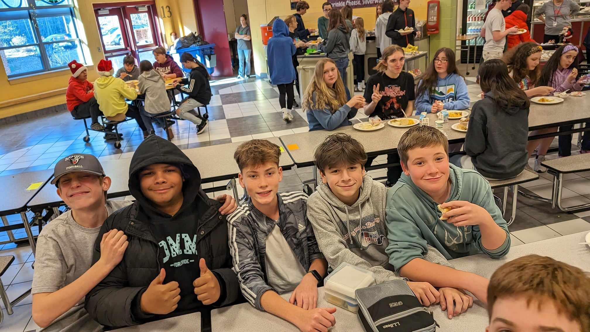 A group of young boys sitting at a table in a cafeteria