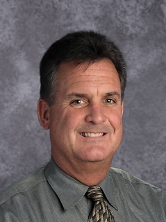 A professional man wearing a tie and shirt with a pleasant expression on his face.