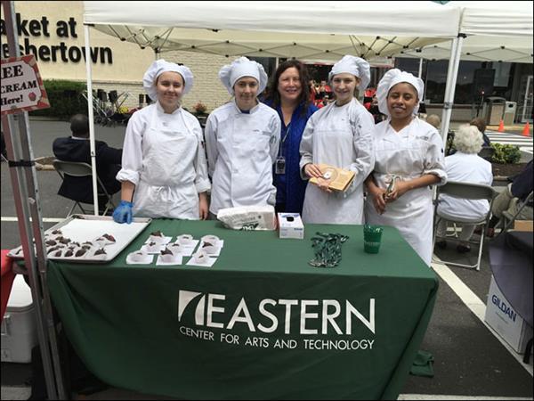 A group of chefs standing behind a table with food, showcasing their culinary skills and creations.