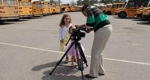 Two girls and a teacher making a video at the parking lot