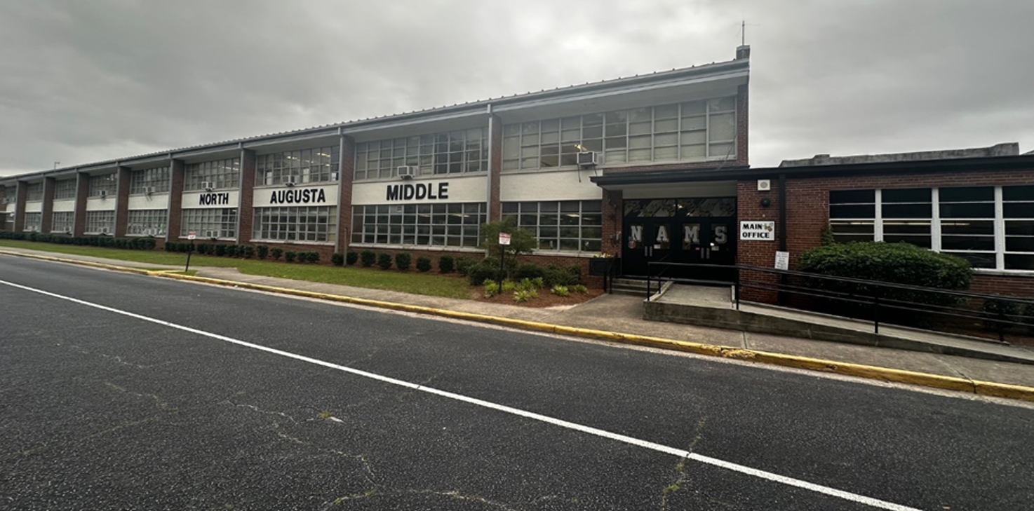 Exterior of 1950s-era school with windows and window units. 