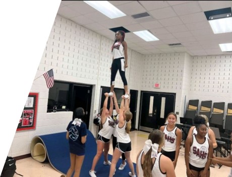 About 10 cheerleaders practicing stunts. 