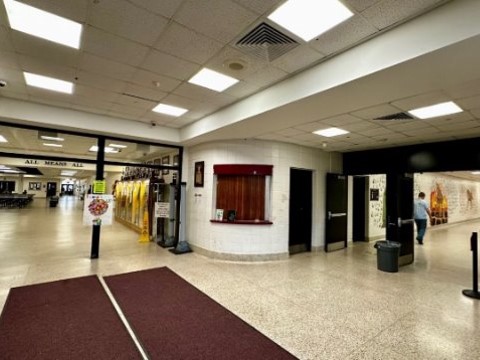 Large entryway with maroon runners, a ticket booth, and the opening to two hallways. 