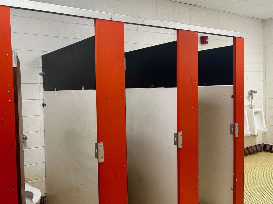 Three red, black and silver restroom stalls. 