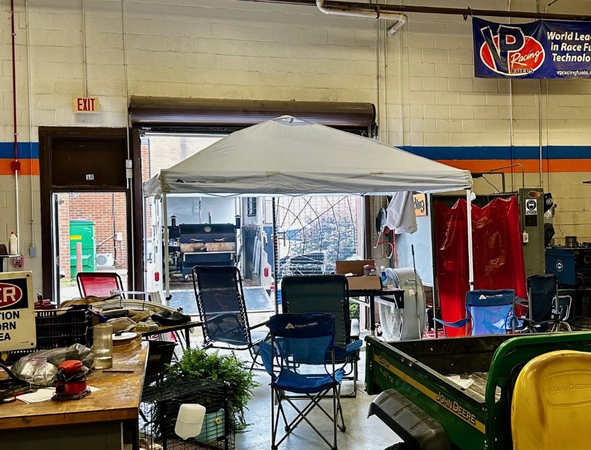 Warehouse-looking space with a tent inside, folding chairs, various equipment, and signage. 