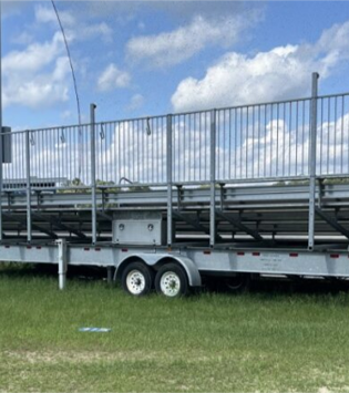 Steel bleachers that are on rolling wheels in a field with grass and blue skies. 