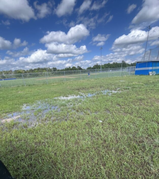 Open athletic field with blue skies, The field has considerable flooding. 