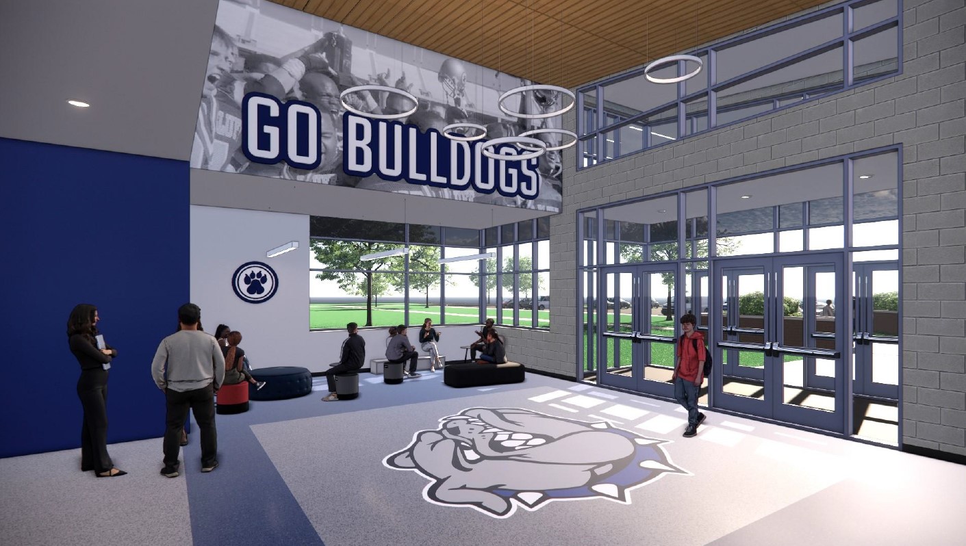 An open large entry way to a school building with lots of windows, high ceilings, and a  football mural that reads, "Go Bulldogs."