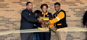 Three people cutting a ribbon