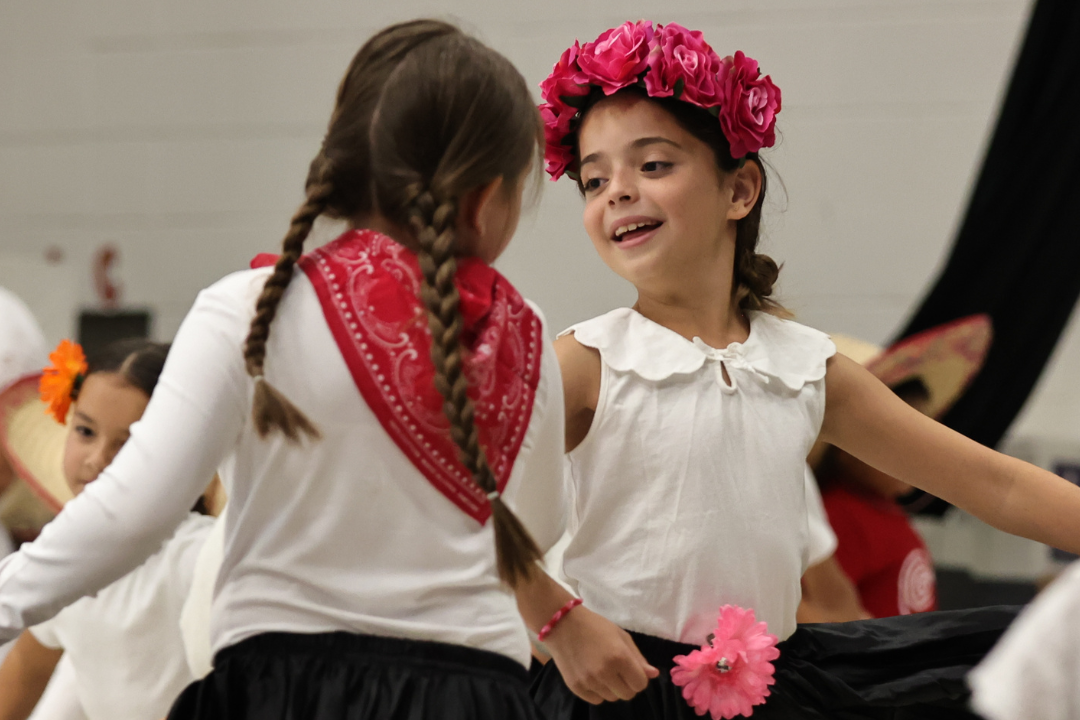 Two students dancing with red roses in the hair and smiling
