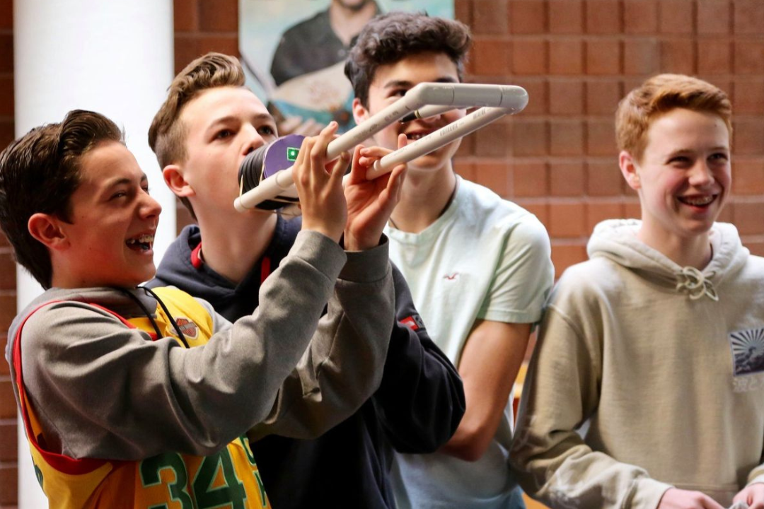 Four students smiling and laughing as they work with a science experiment.