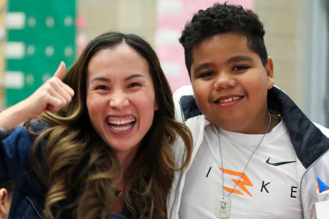 Teacher and student posing and smiling and teacher has her hand in a thumbs up position to show support
