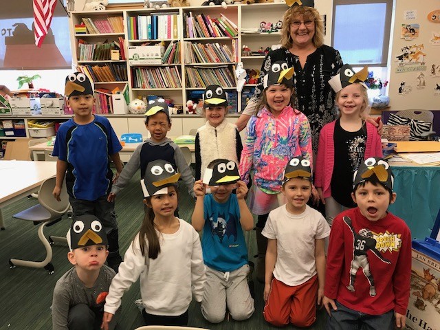 A classroom filled with children wearing adorable penguin hats, creating a lively and playful atmosphere.