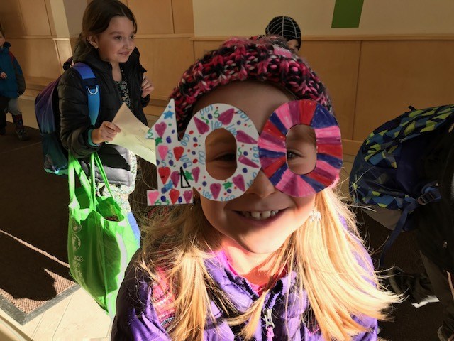 A girl wearing a paper hat with the number 100 on it, celebrating a special occasion.